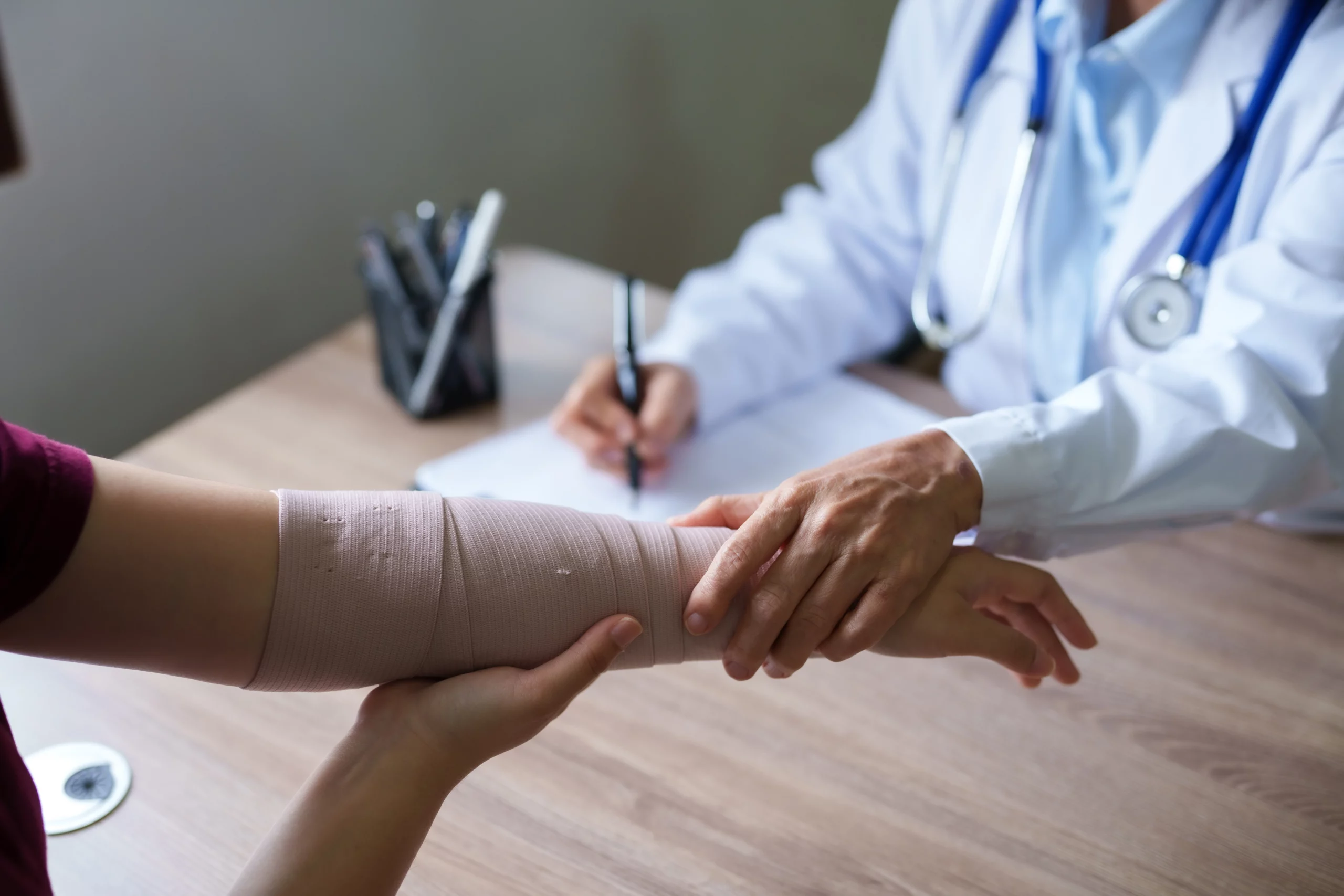 Doctor examining patient’s bandaged arm, illustrating Missouri workers’ comp medical treatment and choosing a treating physician