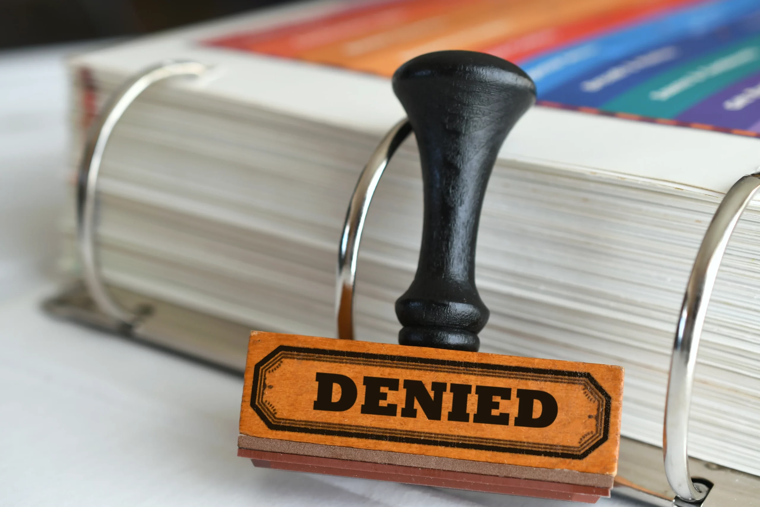 Denied workers’ compensation claim stamp on case file binder, symbolizing rejected workplace injury benefits and the need to appeal the denial.